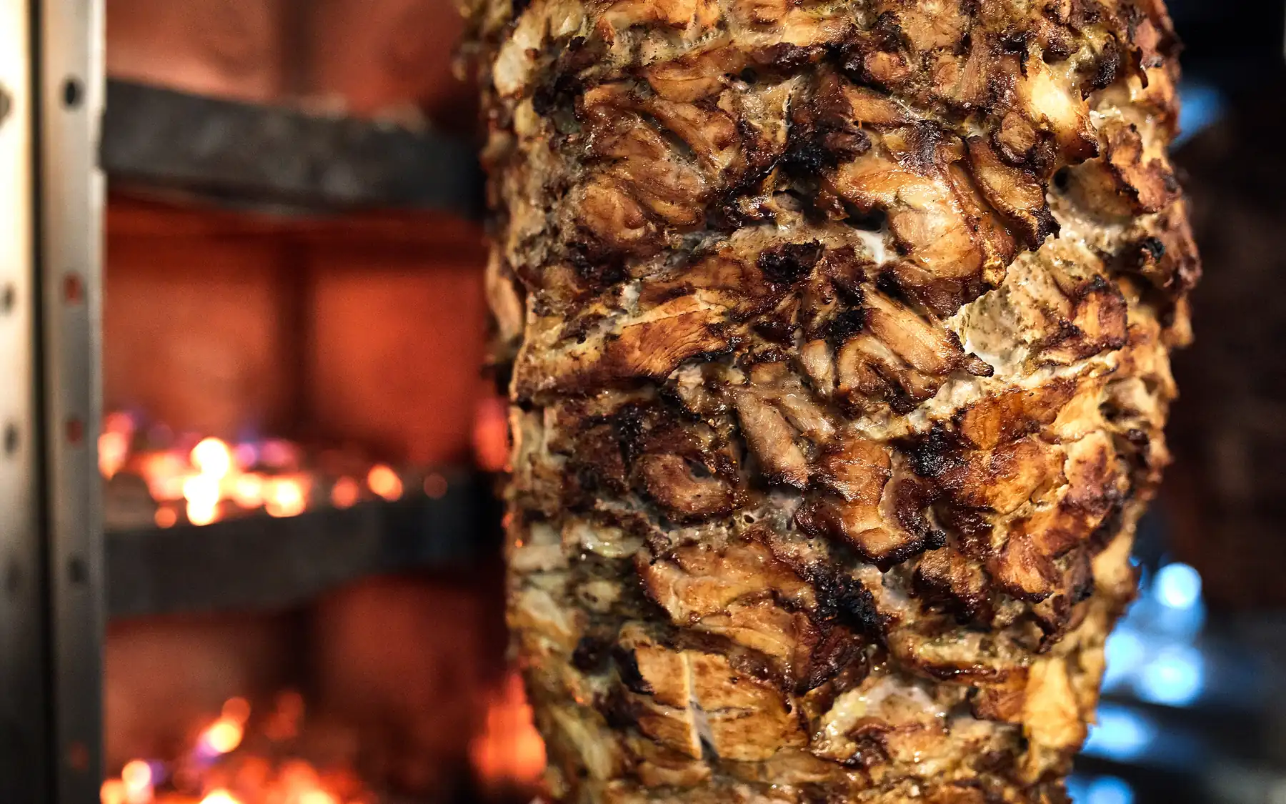 Un asador vertical de gyros girando delante del fuego