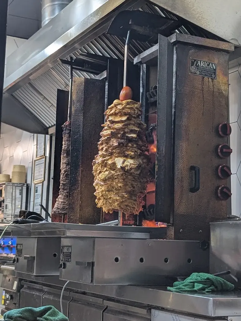 El asador de gyros dentro de Gyros Craft, con la carne montada en el eje vertical